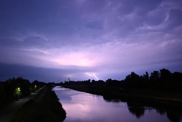 A lightning strikes during a storm over a canal in Sint-Pieters-Leeuw, near Brussels, on June 28, 2026. (Photo by Nicolas TUCAT / AFP)