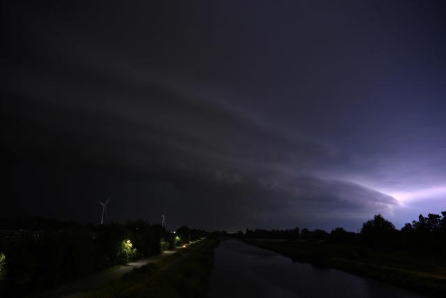 Lightnings flashes in the clouds as a severe storm looms over a canal in Sint-Pieters-Leeuw, near Brussels, on June 28, 2026. (Photo by Nicolas TUCAT / AFP)
