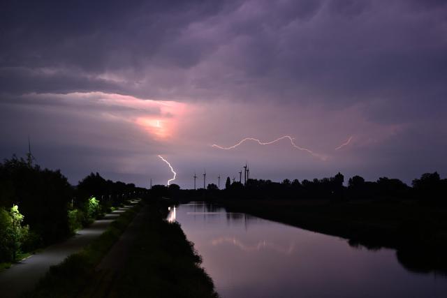 A lightning strikes during a storm over a canal in Sint-Pieters-Leeuw, near Brussels, on June 28, 2026. (Photo by Nicolas TUCAT / AFP)