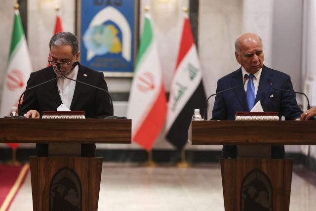 Iranian Foreign Minister Abbas Araqchi (L) and Iraqi Foreign Minister Fuad stand at their lecturns as they arrange their notes prior to the start of their joint press conference following a meeting in Baghdad on July 28, 2026. Iran's foreign minister warned on June 28, that any challenge to the country's control of the strategic Strait of Hormuz would increase tensions despite ongoing peace negotiations to end the Middle East war. (Photo by AHMAD AL-RUBAYE / AFP)