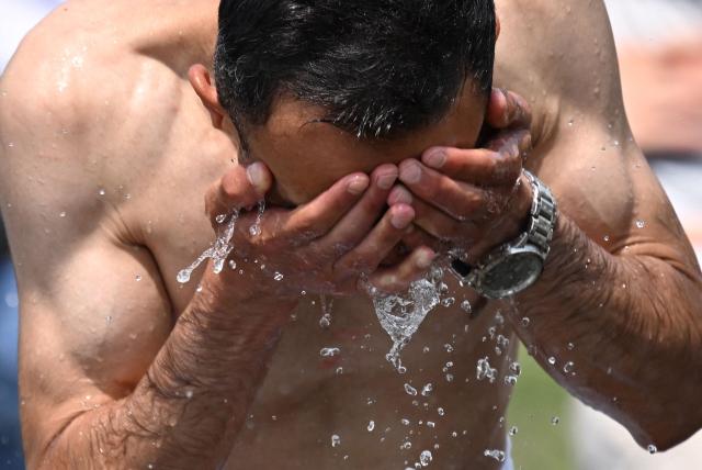 A man cools off with the water of a fountain in Berlin on June 28, 2026, as the German capital is expected to reach temperatures around 40 degrees Celsius during a heatwave in Europe. Tens of millions are braving a weekend of extreme temperatures in Europe as a deadly heatwave moves eastwards, with some countries announcing rising death tolls and health services warning of saturation. While some mild relief is expected Sunday in western Europe, German forecasters are warning that more temperature records could still be broken over the weekend as eastern countries issue a slew of red alerts for the coming days. (Photo by RALF HIRSCHBERGER / AFP)