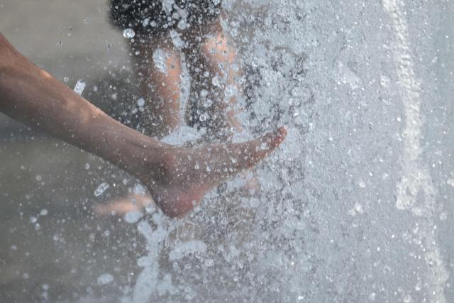 People cool off with the water of a fountain in Berlin on June 28, 2026, as the German capital is expected to reach temperatures around 40 degrees Celsius during a heatwave in Europe. Tens of millions are braving a weekend of extreme temperatures in Europe as a deadly heatwave moves eastwards, with some countries announcing rising death tolls and health services warning of saturation. While some mild relief is expected Sunday in western Europe, German forecasters are warning that more temperature records could still be broken over the weekend as eastern countries issue a slew of red alerts for the coming days. (Photo by RALF HIRSCHBERGER / AFP)