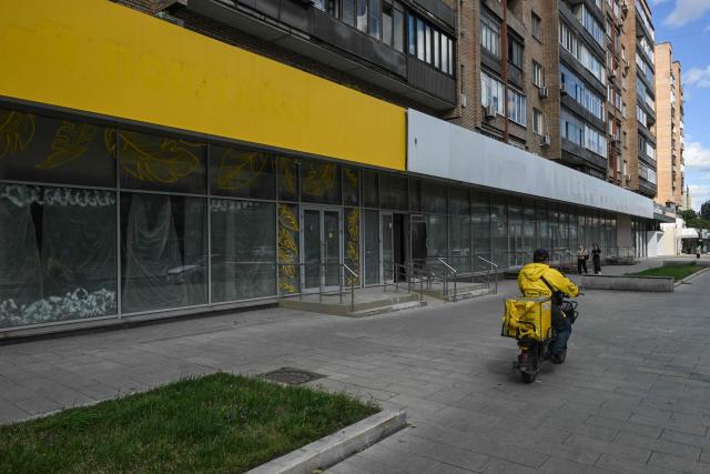 A delivery man rides a bike past the empty display windows of closed shops in Moscow on June 28, 2026. (Photo by Igor IVANKO / AFP)