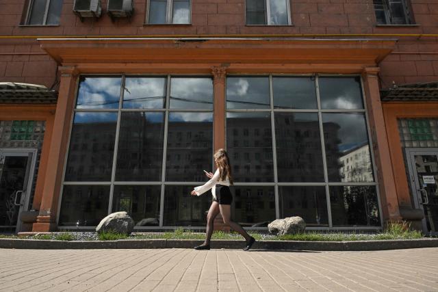 A woman walks past the empty display windows of a closed shop in Moscow on June 28, 2026. (Photo by Igor IVANKO / AFP)