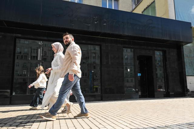 People walk past the empty display windows of closed shops in Moscow on June 28, 2026. (Photo by Igor IVANKO / AFP)