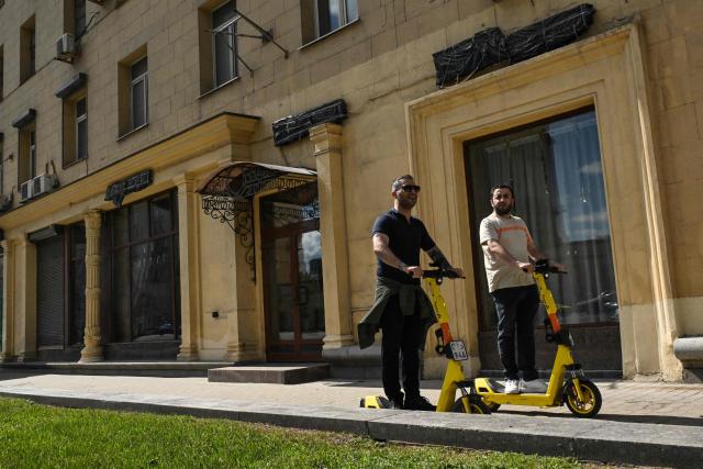 People ride scooters past the empty display windows of closed shops in Moscow on June 28, 2026. (Photo by Igor IVANKO / AFP)