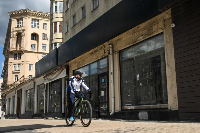 A man cycles past the empty display windows of closed shops in Moscow on June 28, 2026. (Photo by Igor IVANKO / AFP)