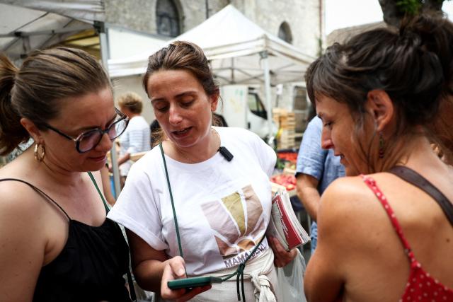 National secretary of French left-wing The Ecologistes party Marine Tondelier (C) speaks with customers at the market in Issigeac, southwestern France on June 28, 2026, as part of a tour of France in an electric van. (Photo by ROMAIN PERROCHEAU / AFP)