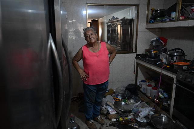 Maria Esther Bernal shows her house partially damaged by the earthquakes during an interview with AFP in Catia La Mar, La Guaira state, Venezuela, on June 28, 2026. Thousands of rescuers, relatives and volunteers dig day and night through mounds of concrete to find survivors of the earthquakes that struck Venezuela more than three days ago, leaving nearly 1,500 dead and tens of thousands missing. (Photo by Juan BARRETO / AFP)