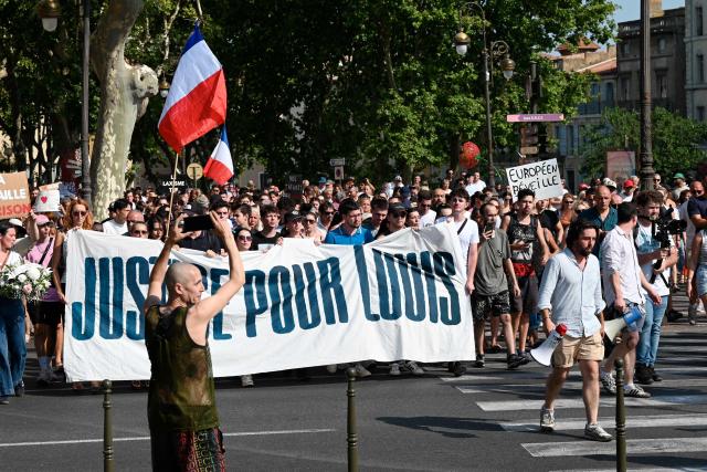 People hold a national flag and a banner reading "Justice for Louis" during a rally in the memory of Louis, a 17-year-old boy who died after being beaten up by five young people during an ambush, in Narbonne, southern France, on June 28, 2026. France's Interior Minister condemned in an interview the “exploitation of the case by the far right” involving the 17-year-old boy and said that five young men, aged between 16 and 20, have been charged with murder in connection with this case. (Photo by Matthieu RONDEL / AFP)
