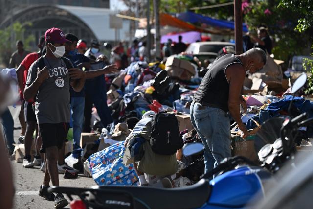 Residents sort through piles of donated clothing in Catia La Mar, La Guaira state, Venezuela, on June 28, 2026, following earthquakes. Thousands of rescuers, relatives and volunteers dig day and night through mounds of concrete to find survivors of the earthquakes that struck Venezuela more than three days ago, leaving nearly 1,500 dead and tens of thousands missing. (Photo by Juan BARRETO / AFP)