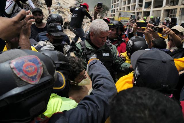 Rescuers carry a person after being pulled alive from the rubble of a collapsed building in Caraballeda, La Guaira state, Venezuela, on June 28, 2026, following earthquakes. Thousands of rescuers, relatives and volunteers dig day and night through mounds of concrete to find survivors of the earthquakes that struck Venezuela more than three days ago, leaving nearly 1,500 dead and tens of thousands missing. (Photo by Mauricio VALENZUELA / AFP)
