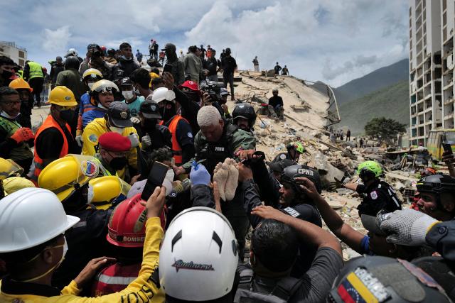 Rescuers carry a person after being pulled alive from the rubble of a collapsed building in Caraballeda, La Guaira state, Venezuela, on June 28, 2026, following earthquakes. Thousands of rescuers, relatives and volunteers dig day and night through mounds of concrete to find survivors of the earthquakes that struck Venezuela more than three days ago, leaving nearly 1,500 dead and tens of thousands missing. (Photo by Mauricio VALENZUELA / AFP)