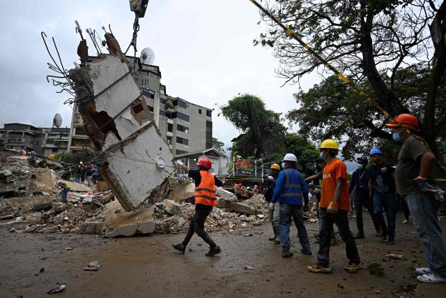 Workers remove debris from a collapsed building in the San Bernardino neighborhood of Caracas on June 28, 2026, following earthquakes. Thousands of rescuers, relatives and volunteers dig day and night through mounds of concrete to find survivors of the earthquakes that struck Venezuela more than three days ago, leaving nearly 1,500 dead and tens of thousands missing. (Photo by Federico PARRA / AFP)