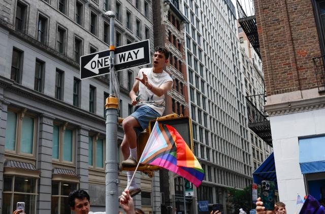 A Progress Pride Flag is waves as people watch the annual New York City Pride March in New York on June 28, 2026. (Photo by kena betancur / AFP)