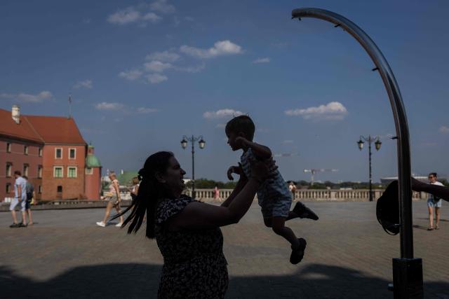 A Woman cools off her son under a water tap on the Royal Castle Square in Warsaw's Old Town as thermometers show record temperatures during a heatwave that has reached Poland on June 28, 2026 (Photo by Wojtek RADWANSKI / AFP)