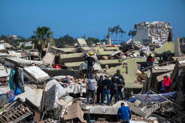 Volunteers and residents search for survivors on the rubble of collapsed buildings in Caraballeda, La Guaira state, Venezuela, on June 28, 2026, following earthquakes. Thousands of rescuers, relatives and volunteers dig day and night through mounds of concrete to find survivors of the earthquakes that struck Venezuela more than three days ago, leaving nearly 1,500 dead and tens of thousands missing. (Photo by Miguel MEDINA / POOL / AFP)