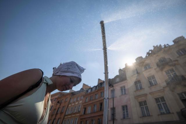 A woman cools off under a water spray on the Royal Castle Square in Warsaw's Old Town as thermometers show record temperatures during a heatwave that has reached Poland on June 28, 2026 (Photo by Wojtek RADWANSKI / AFP)