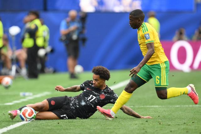 Canada's midfielder #17 Tajon Buchanan slides for the ball past South Africa's defender #06 Aubrey Modiba during the 2026 World Cup round of 32 football match between South Africa and Canada at the Los Angeles Stadium in Inglewood on June 28, 2026.  (Photo by Patrick T. Fallon / AFP)