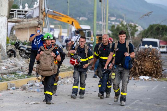 Members of the French Civil Security Training and Intervention Regiment (UIISC 7) walk in an area affected by building collapses in La Guaira state, Venezuela, on June 28, 2026, following earthquakes. Thousands of rescuers, relatives and volunteers dig day and night through mounds of concrete to find survivors of the earthquakes that struck Venezuela more than three days ago, leaving nearly 1,500 dead and tens of thousands missing. (Photo by Miguel MEDINA / POOL / AFP)