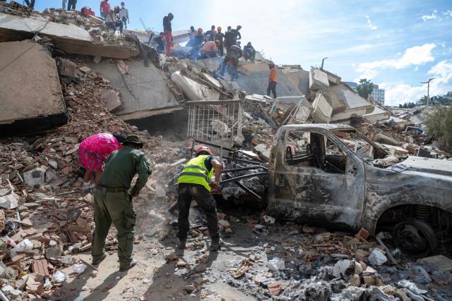 Rescuers and volunteers search for survivors on the rubble of a collapsed building in La Guaira state, Venezuela, on June 28, 2026, following earthquakes. Thousands of rescuers, relatives and volunteers dig day and night through mounds of concrete to find survivors of the earthquakes that struck Venezuela more than three days ago, leaving nearly 1,500 dead and tens of thousands missing. (Photo by Miguel MEDINA / POOL / AFP)