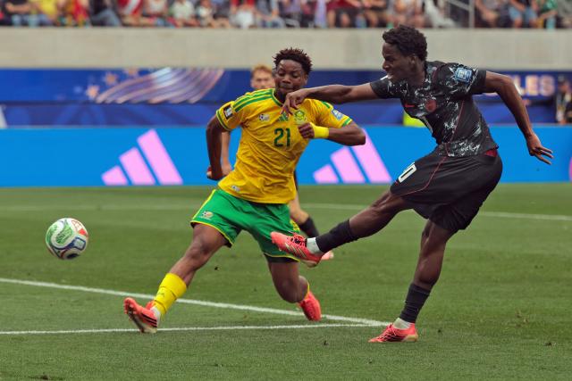 Canada's forward #10 Jonathan David (R) kicks the ball past South Africa's defender #21 Ime Okon during the 2026 World Cup round of 32 football match between South Africa and Canada at the Los Angeles Stadium in Inglewood on June 28, 2026.  (Photo by Etienne LAURENT / AFP)