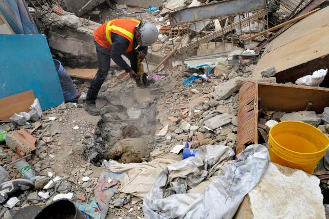 A rescuer uses a grinder while trying to retrieve a body in Caraballeda, La Guaira State, Venezuela on June 28, 2026, following twin earthquakes. Thousands of rescuers, relatives and volunteers dig day and night through mounds of concrete to find survivors of the earthquakes that struck Venezuela more than three days ago, leaving nearly 1,500 dead and tens of thousands missing. (Photo by Mauricio VALENZUELA / AFP)
