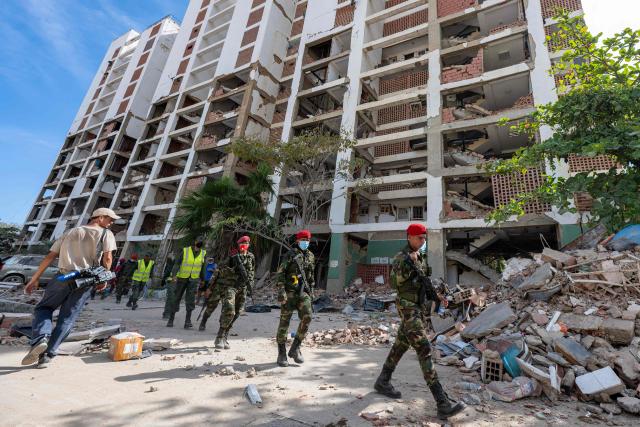 Venezuelan Bolivarian Army soldiers walk in front of a damaged building Caraballeda, La Guaira state, Venezuela, on June 28, 2026, following twin earthquakes. Thousands of rescuers, relatives and volunteers dig day and night through mounds of concrete to find survivors of the earthquakes that struck Venezuela more than three days ago, leaving nearly 1,500 dead and tens of thousands missing. (Photo by Miguel MEDINA / POOL / AFP)