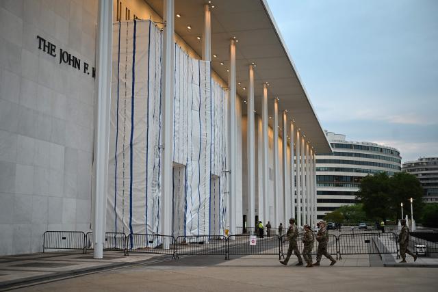 National Gaurd troops patrol outside the Kennedy Center, the facade of which remains covered with a tarp, in Washington, DC, on June 28, 2026. A US federal judge asked on June 24 for an explanation for why a tarpaulin continues to cover the facade of the Kennedy Center where President Donald Trump's name was recently removed. District Judge Christopher Cooper gave the board of trustees of the performing arts venue until the end of July to explain "the purpose for and status of the tarp and scaffolding that Defendants have erected on the front portico of the Center." (Photo by Alex WROBLEWSKI / AFP)