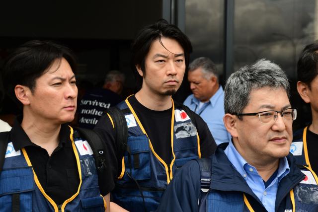Rescuers of the Japan International Cooperation Agency walk on arrival at the Arturo Michelena international airport in Valencia, Carabobo state, Venezuela, to help in search operations following twin earthquakes, on June 28, 2026. Thousands of rescuers, relatives and volunteers dig day and night through mounds of concrete to find survivors of the earthquakes that struck Venezuela more than three days ago, leaving nearly 1,500 dead and tens of thousands missing. (Photo by Jacinto OLIVEROS / AFP)