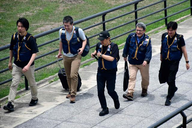 Rescuers of the Japan International Cooperation Agency walk on arrival at the Arturo Michelena international airport in Valencia, Carabobo state, Venezuela, to help in search operations following twin earthquakes, on June 28, 2026. Thousands of rescuers, relatives and volunteers dig day and night through mounds of concrete to find survivors of the earthquakes that struck Venezuela more than three days ago, leaving nearly 1,500 dead and tens of thousands missing. (Photo by Jacinto OLIVEROS / AFP)