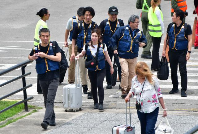 Rescuers of the Japan International Cooperation Agency walk on arrival at the Arturo Michelena international airport in Valencia, Carabobo state, Venezuela, to help in search operations following twin earthquakes, on June 28, 2026. Thousands of rescuers, relatives and volunteers dig day and night through mounds of concrete to find survivors of the earthquakes that struck Venezuela more than three days ago, leaving nearly 1,500 dead and tens of thousands missing. (Photo by Jacinto OLIVEROS / AFP)