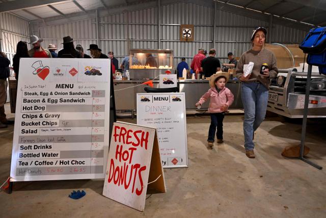 People order food at the Marree Australasian Camel Cup meet in the South Australian outback town of Marree on June 27, 2026. The Camel Cup is a much-loved outback event celebrating camel racing, Afghan cameleer heritage, community and culture. Camels were instrumental in helping settlers open the outback of Australia to development until trains took over. (Photo by William WEST / AFP)