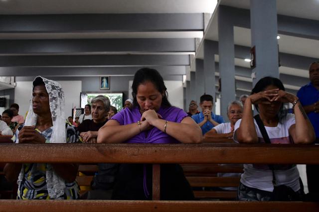 Locals pray during a mass within the NAtional Day of Prayer for the quake victims in Valencia, Carabobo state, Venezuela, following twin earthquakes, on June 28, 2026. Volunteers and emergency brigades with rescue dogs continue lifting mountains of rubble on in search of survivors of the twin earthquake that struck Venezuela four days ago, which completely brought down nearly 200 buildings and left at least 1,450 dead and tens of thousands missing. (Photo by Jacinto OLIVEROS / AFP)