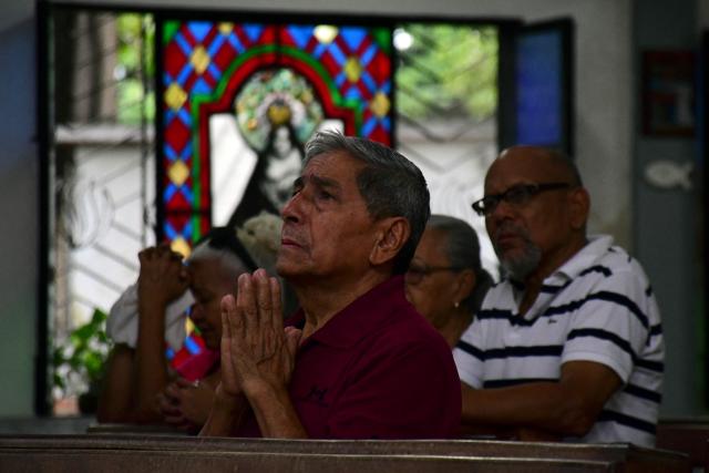 Locals pray during a mass within the NAtional Day of Prayer for the quake victims in Valencia, Carabobo state, Venezuela, following twin earthquakes, on June 28, 2026. Volunteers and emergency brigades with rescue dogs continue lifting mountains of rubble on in search of survivors of the twin earthquake that struck Venezuela four days ago, which completely brought down nearly 200 buildings and left at least 1,450 dead and tens of thousands missing. (Photo by Jacinto OLIVEROS / AFP)