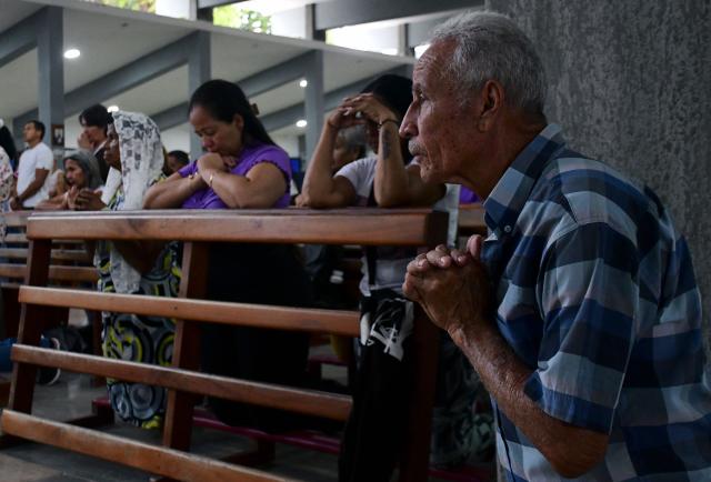 Locals pray during a mass within the National Day of Prayer for the quake victims in Valencia, Carabobo state, Venezuela, following twin earthquakes, on June 28, 2026. Volunteers and emergency brigades with rescue dogs continue lifting mountains of rubble in search of survivors of the twin earthquake that struck Venezuela four days ago, which completely brought down nearly 200 buildings and left at least 1,450 dead and tens of thousands missing. (Photo by Jacinto OLIVEROS / AFP)