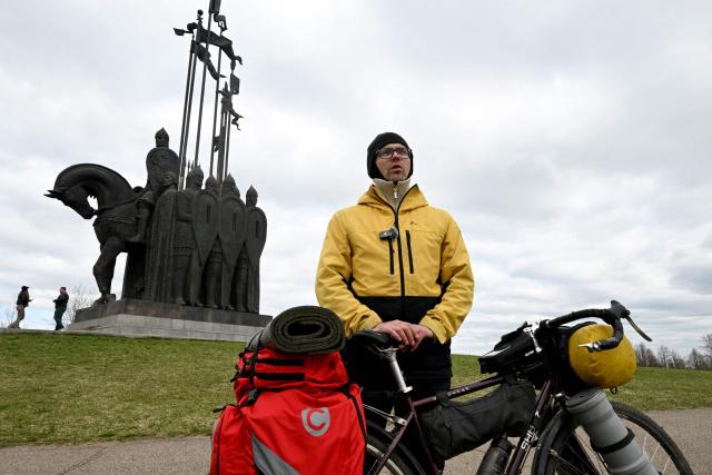 Dmitry Zhukov, the 37-year-old cycletourer, talks to AFP reporters in front of a monument to the Battle on the Ice, honouring the 1242 battle on the frozen Lake Peipus (Chudskoye) when Russian medieval prince Alexander Nevsky repelled a force of Teutonic Knights who wanted to convert Russia to Catholicism, in the Pskov region on April 20, 2026. (Photo by Olga MALTSEVA / AFP)