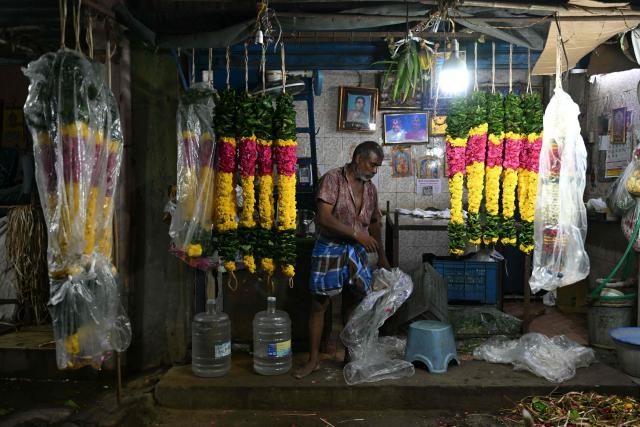 A vendor sorts garlands after opening his flower shop early morning in Chennai on June 29, 2026. (Photo by R.Satish BABU / AFP)