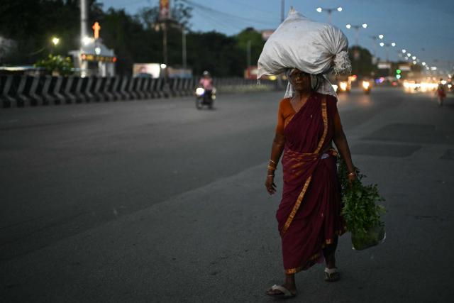 A vendor carrying groceries walks to her shop early morning in Chennai on June 29, 2026. (Photo by R. Satish BABU / AFP)