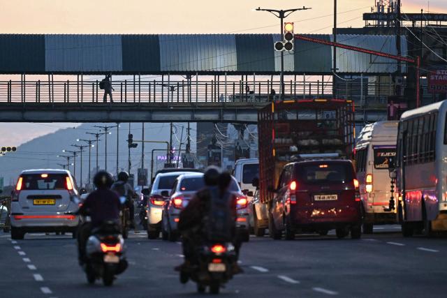 A pedestrian walks on a foot over bridge early morning in Chennai on June 29, 2026. (Photo by R.Satish BABU / AFP)