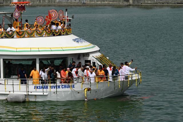 A Hindu priest collects holy water from river Sabarmati during Jal Yatra, a religious procession from Lord Jagannath temple to Sabarmati riverfront in Ahmedabad on June 29, 2026. (Photo by Shammi MEHRA / AFP)