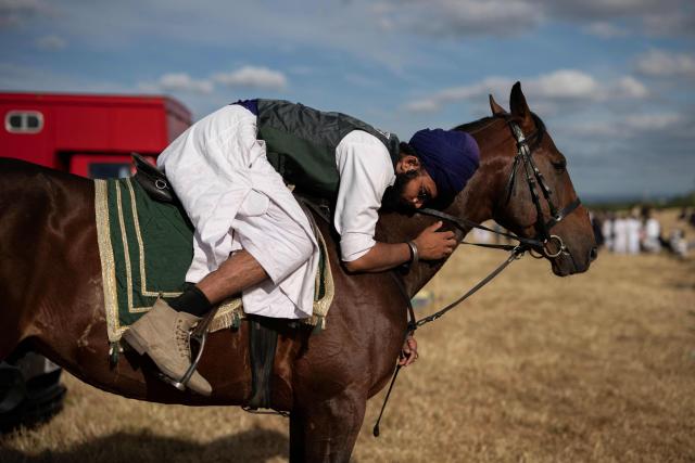 A team member with the Khari Shreef Club embraces his horse as he prepares to compete at the Bury Championship Neza Bazi event in Unsworth, near Bury, northern England on June 28, 2026. Neza Bazi, also known as tent pegging, sees riders on horseback use a lance or sword to strike and pick up small targets from the ground whilst at full gallop. The sport is believed to have originated in the Indian subcontinent during the Middle Ages. It is one of only ten equestrian sports officially recognised by the International Equestrian Federation. (Photo by Oli SCARFF / AFP)