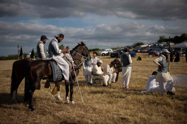 Riders and team members relax after competing at the Bury Championship Neza Bazi event in Unsworth, near Bury, northern England on June 28, 2026. Neza Bazi, also known as tent pegging, sees riders on horseback use a lance or sword to strike and pick up small targets from the ground whilst at full gallop. The sport is believed to have originated in the Indian subcontinent during the Middle Ages. It is one of only ten equestrian sports officially recognised by the International Equestrian Federation. (Photo by Oli SCARFF / AFP)