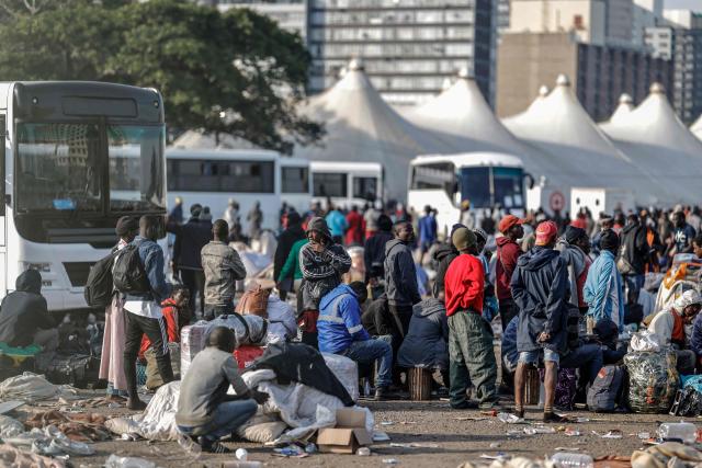 TOPSHOT - Undocumented migrants queue to board the last buses leaving the Durban Drive In in central Durban, on June 29, 2026. South Africans President Cyril Ramaphosa vowed on June 25 to crush any attempts to destabilise the nation during planned anti-immigrant marches next week, amid a wave of xenophobia. Citizen-led groups have set Tuesday 30 as a deadline for undocumented foreigners to leave and called for nationwide marches against illegal immigration, marking a crescendo in months of protests that have at times turned violent. (Photo by Marco Longari / AFP)