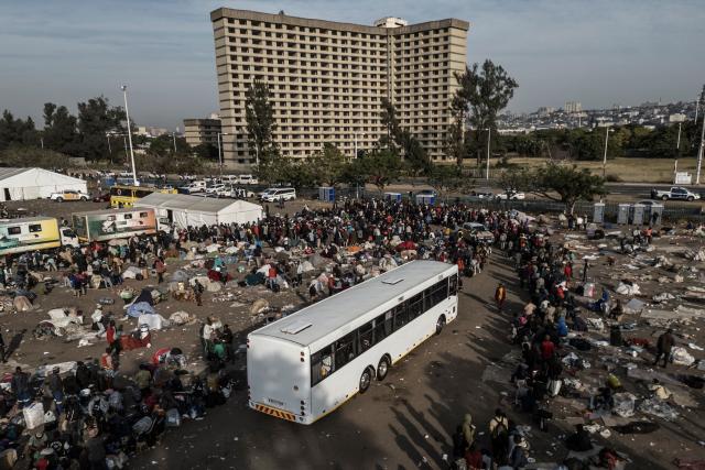 TOPSHOT - An aerial view of the hundreds of undocumented migrants still present at the Durban Drive In in central Durban, on June 29, 2026 before boarding busses that will be taking them back home. South Africans President Cyril Ramaphosa vowed on June 25 to crush any attempts to destabilise the nation during planned anti-immigrant marches next week, amid a wave of xenophobia. Citizen-led groups have set Tuesday 30 as a deadline for undocumented foreigners to leave and called for nationwide marches against illegal immigration, marking a crescendo in months of protests that have at times turned violent. (Photo by MARCO LONGARI / AFP)