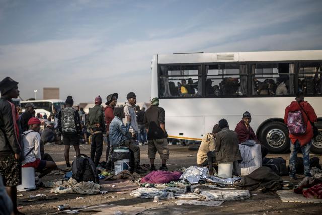 Undocumented migrants line up near a bus at the Durban Drive In in Durban, on June 29, 2026 preparing to leave before the shutting down of the camp and the operation will be transferred to the border with Zimbabwe. South Africans President Cyril Ramaphosa vowed on June 25 to crush any attempts to destabilise the nation during planned anti-immigrant marches next week, amid a wave of xenophobia. Citizen-led groups have set Tuesday 30 as a deadline for undocumented foreigners to leave and called for nationwide marches against illegal immigration, marking a crescendo in months of protests that have at times turned violent. (Photo by MARCO LONGARI / AFP)