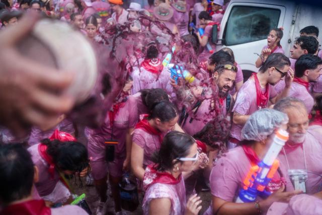 Revellers are doused with red wine during the"Batalla del Vino" (Battle of Wine) in Haro, in the wine producing region of La Rioja, on June 29, 2026. Every year thousands of locals and tourists climb a mountain in the northern Spanish wine producing region of La Rioja to celebrate St. Peter's day by covering each other in red wine using water pistols, back mounted spraying devices, buckets which are randomly poured on heads and into any other available container. (Photo by CESAR MANSO / AFP)