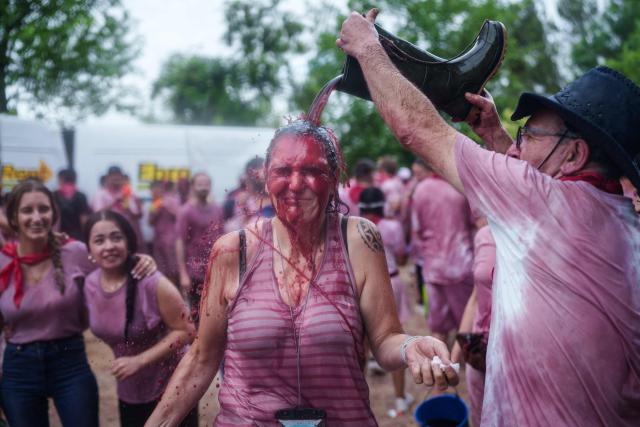 A reveller pours a boot full of red wine on a participant during the"Batalla del Vino" (Battle of Wine) in Haro, in the wine producing region of La Rioja, on June 29, 2026. Every year thousands of locals and tourists climb a mountain in the northern Spanish wine producing region of La Rioja to celebrate St. Peter's day by covering each other in red wine using water pistols, back mounted spraying devices, buckets which are randomly poured on heads and into any other available container. (Photo by CESAR MANSO / AFP)
