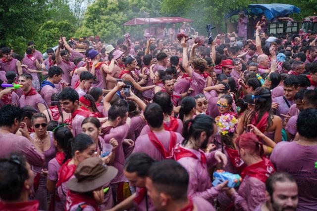 Revellers douse each other with red wine during the"Batalla del Vino" (Battle of Wine) in Haro, in the wine producing region of La Rioja, on June 29, 2026. Every year thousands of locals and tourists climb a mountain in the northern Spanish wine producing region of La Rioja to celebrate St. Peter's day by covering each other in red wine using water pistols, back mounted spraying devices, buckets which are randomly poured on heads and into any other available container. (Photo by CESAR MANSO / AFP)