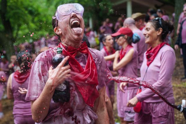 A reveller is doused with red wine during the"Batalla del Vino" (Battle of Wine) in Haro, in the wine producing region of La Rioja, on June 29, 2026. Every year thousands of locals and tourists climb a mountain in the northern Spanish wine producing region of La Rioja to celebrate St. Peter's day by covering each other in red wine using water pistols, back mounted spraying devices, buckets which are randomly poured on heads and into any other available container. (Photo by CESAR MANSO / AFP)